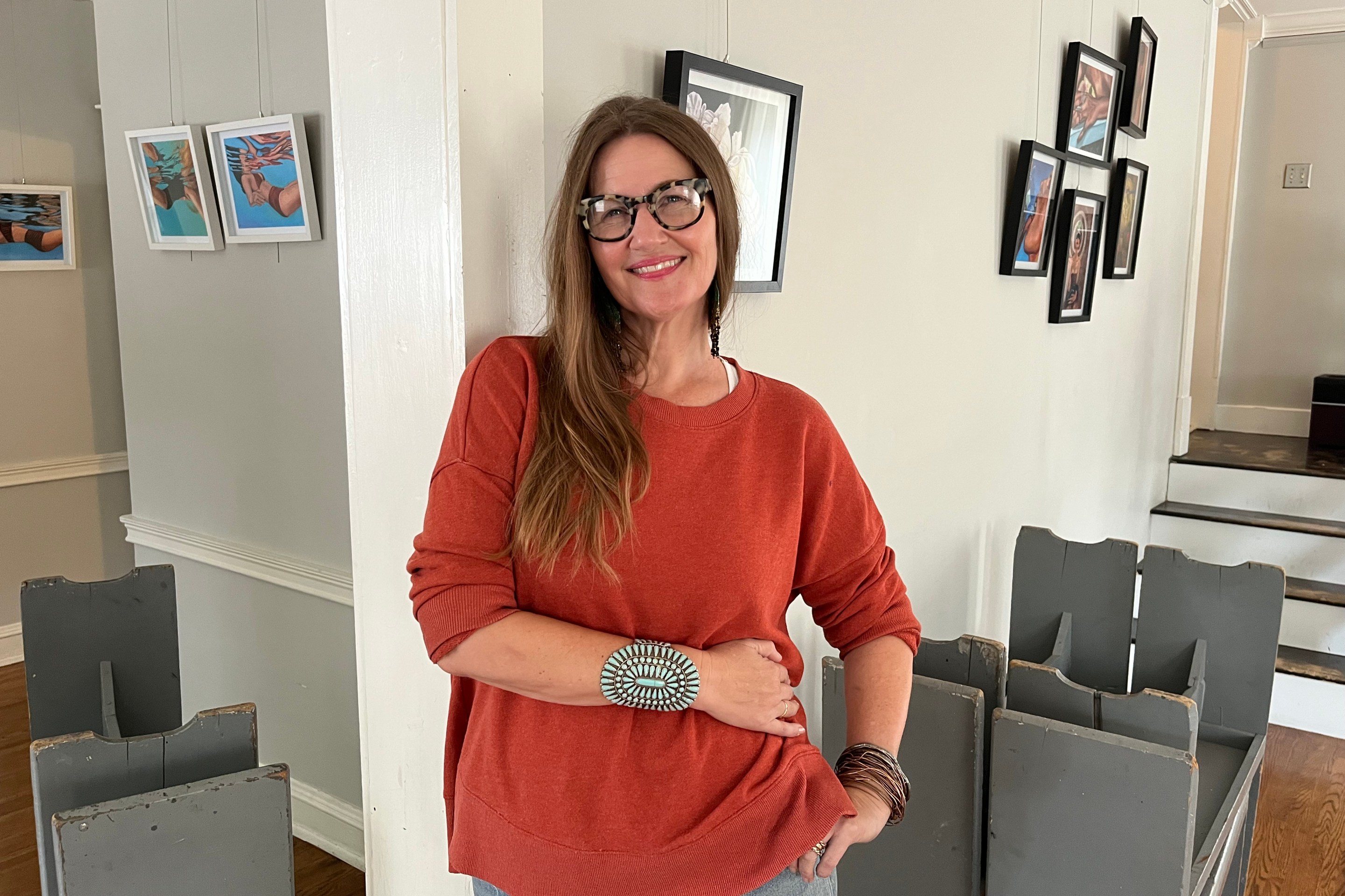 A woman in a comfortable sweater poses for a photo inside of a house.