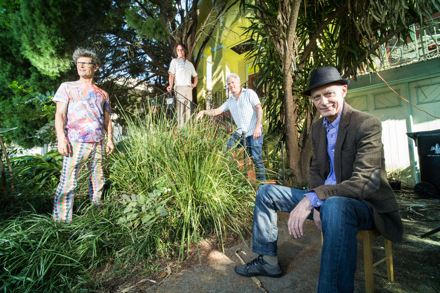 Four men pose for a group photo around a large, green bush.