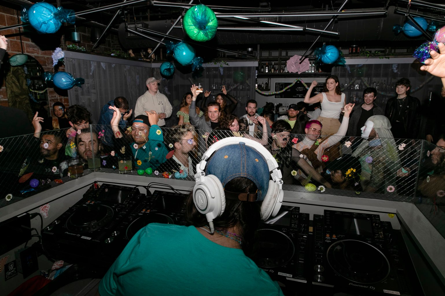 DJ wearing headphones is performing at St. Vitus in front of excited crowd in a packed venue with moody lighting.