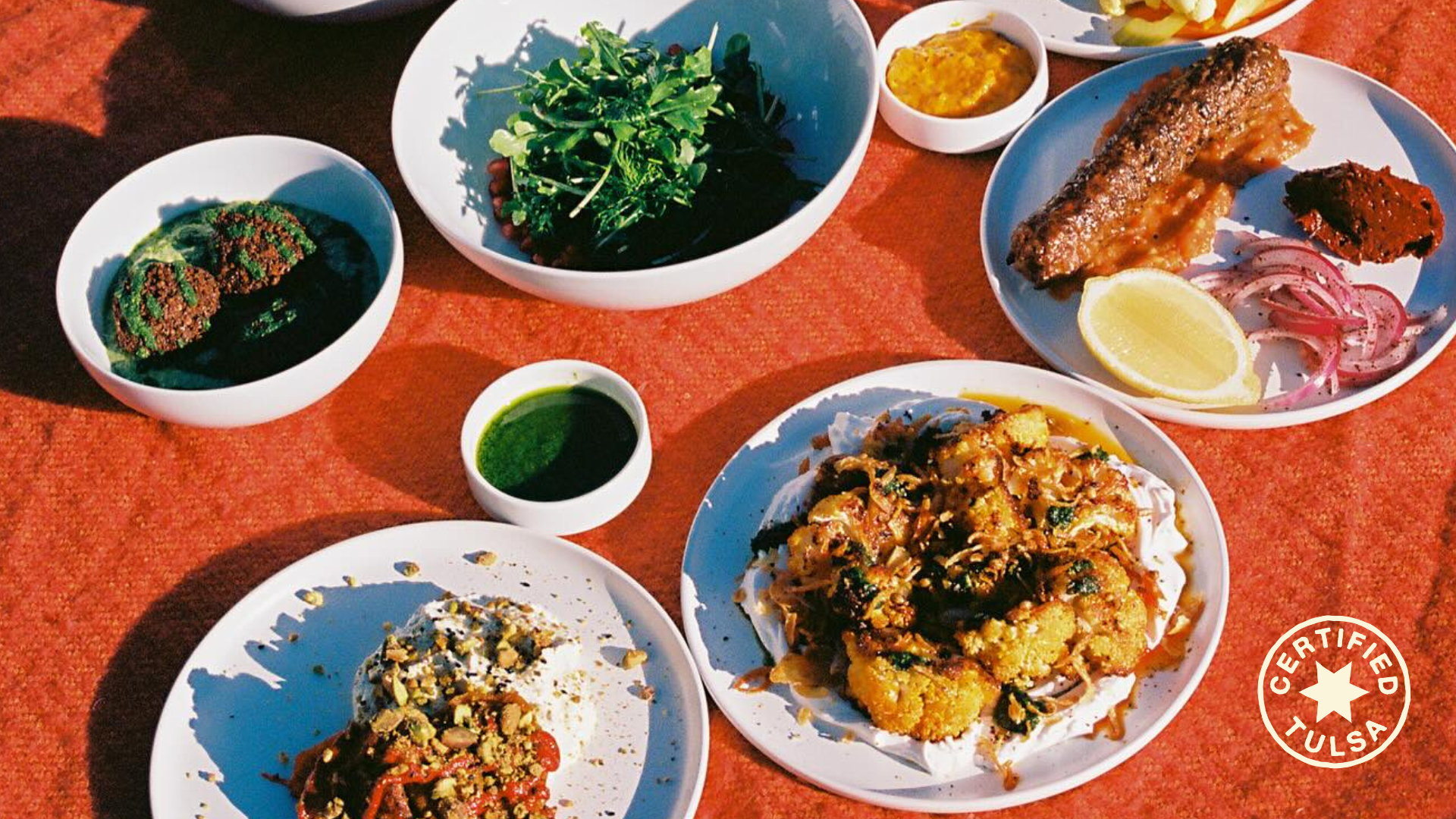 Many courses of of Mediterranean food sits on a red table.