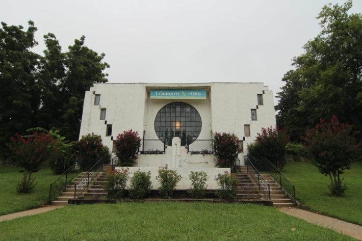 A white art deco-style building with a large circle window stands in the center of the frame.