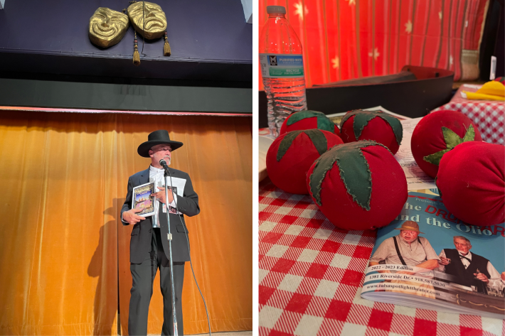 An emcee stands on a stage, side by side with a picture of fake tomatoes.